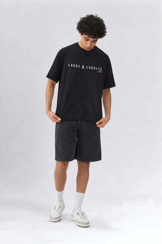 Person wearing a black t-shirt with text and dark shorts on a white background