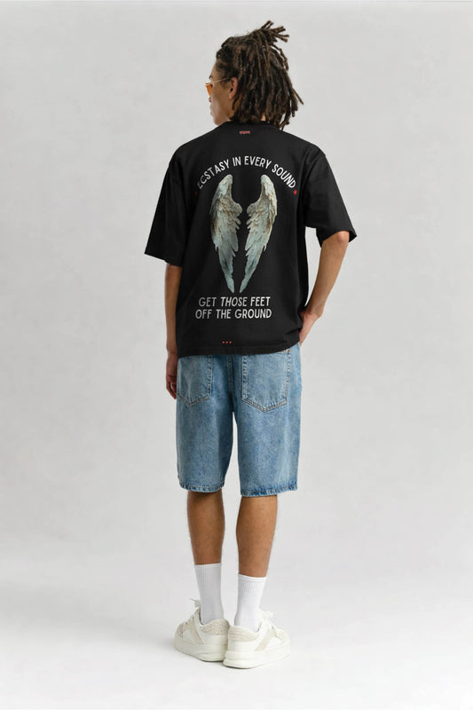 Person wearing a black t-shirt with angel wings graphic and text on a plain background