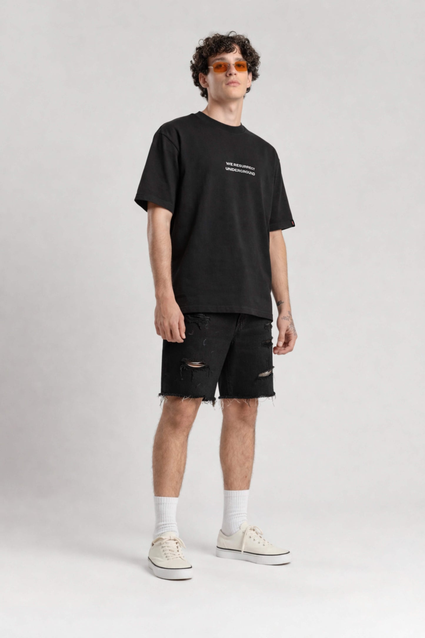 Man wearing a black t-shirt and shorts on a white background