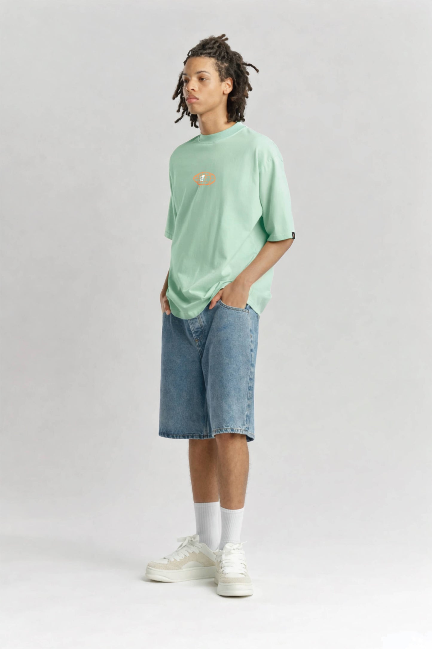 Person wearing a light green t-shirt and denim shorts on a white background