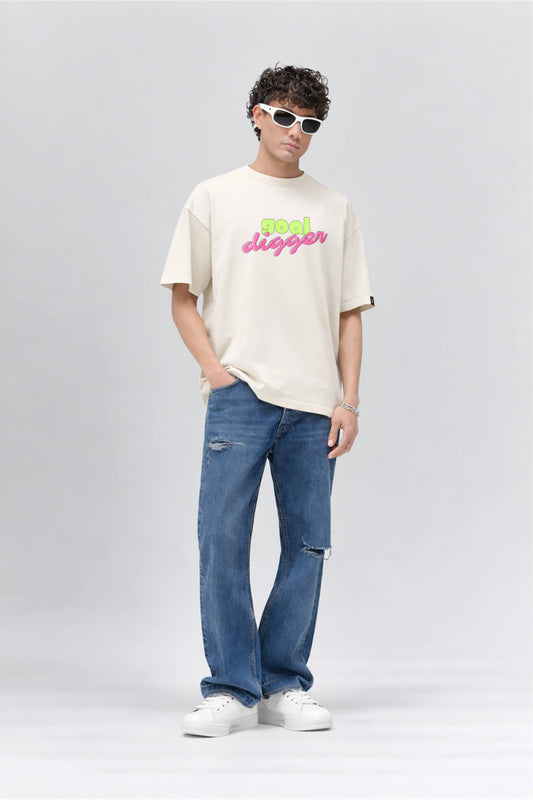 Person wearing an off white t-shirt with colorful text and blue jeans on a gray background