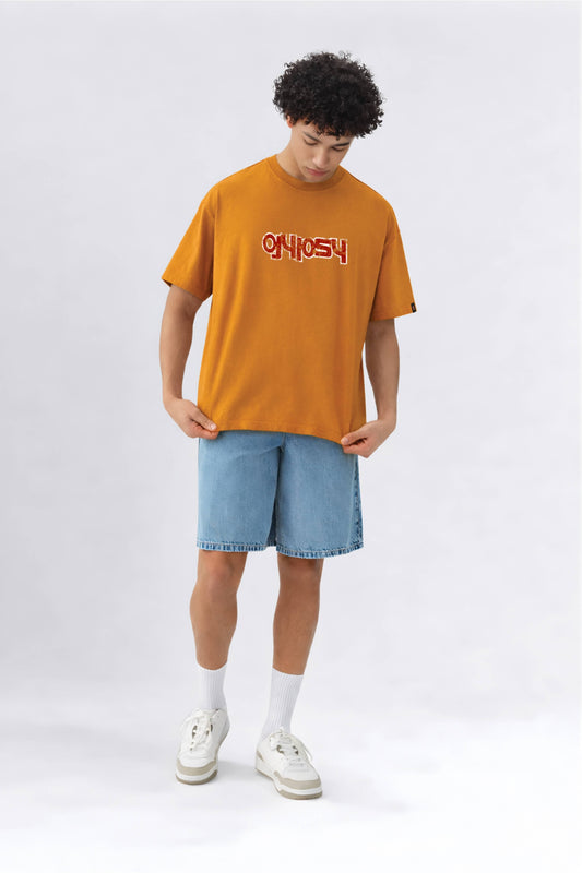 Person wearing an orange t-shirt with text and light blue shorts on a white background