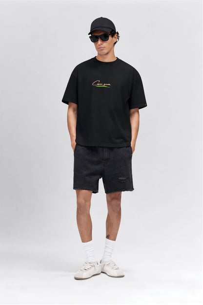 Man wearing a black t-shirt with a logo, black shorts, white sneakers, and a black cap on a white background