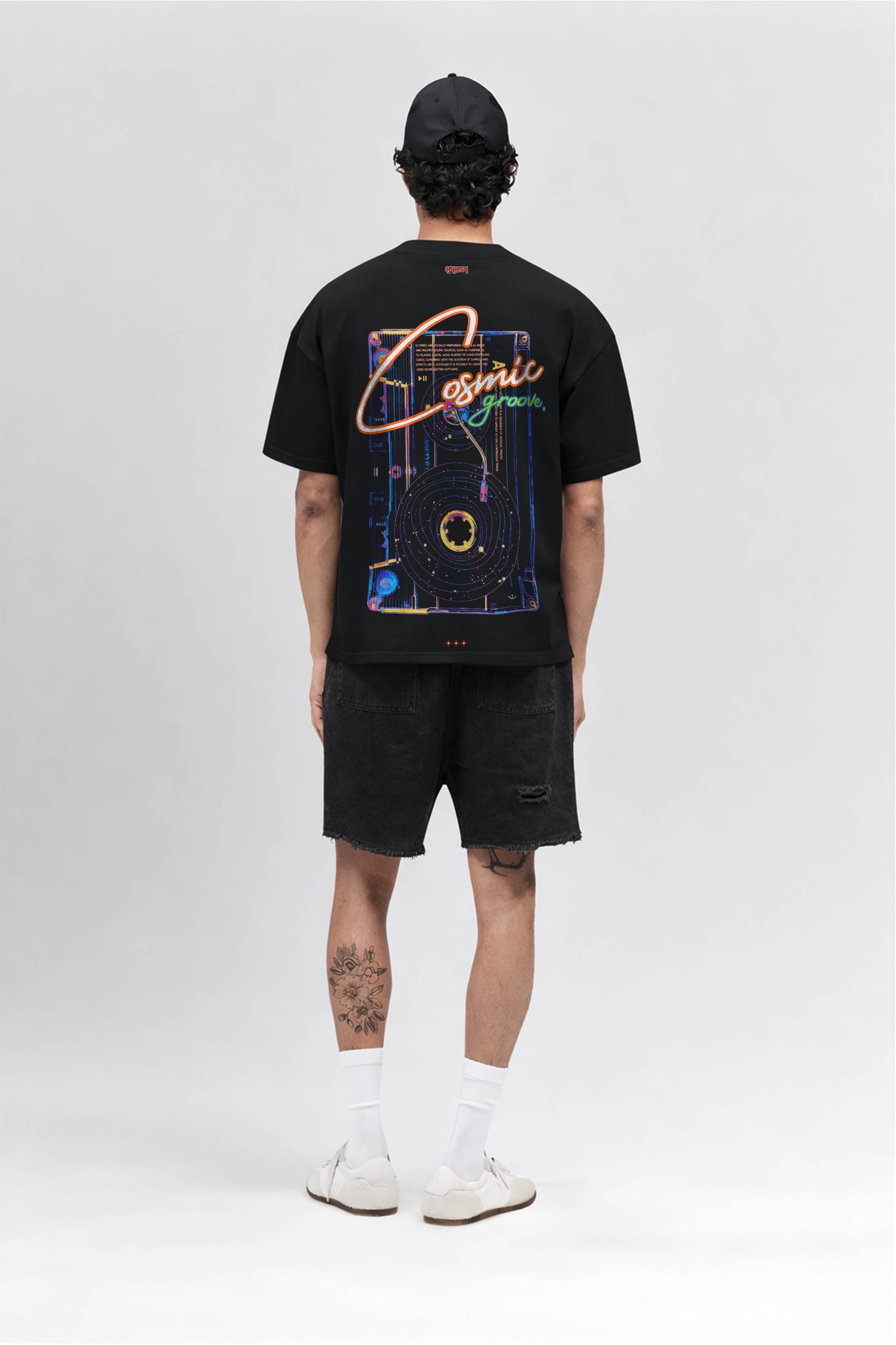Person wearing a black t-shirt with a colorful graphic design on the back, standing against a white background.