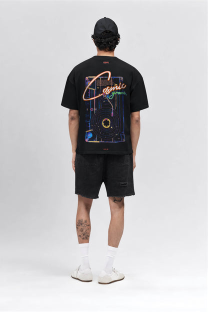Person wearing a black t-shirt with a colorful graphic design on the back, standing against a white background.