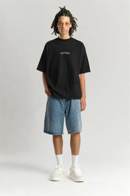 Person wearing a black t-shirt with text, blue shorts, and white sneakers on a light gray background