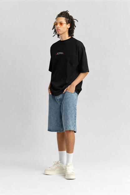 Person wearing a black t-shirt, blue shorts, and white sneakers on a light gray background