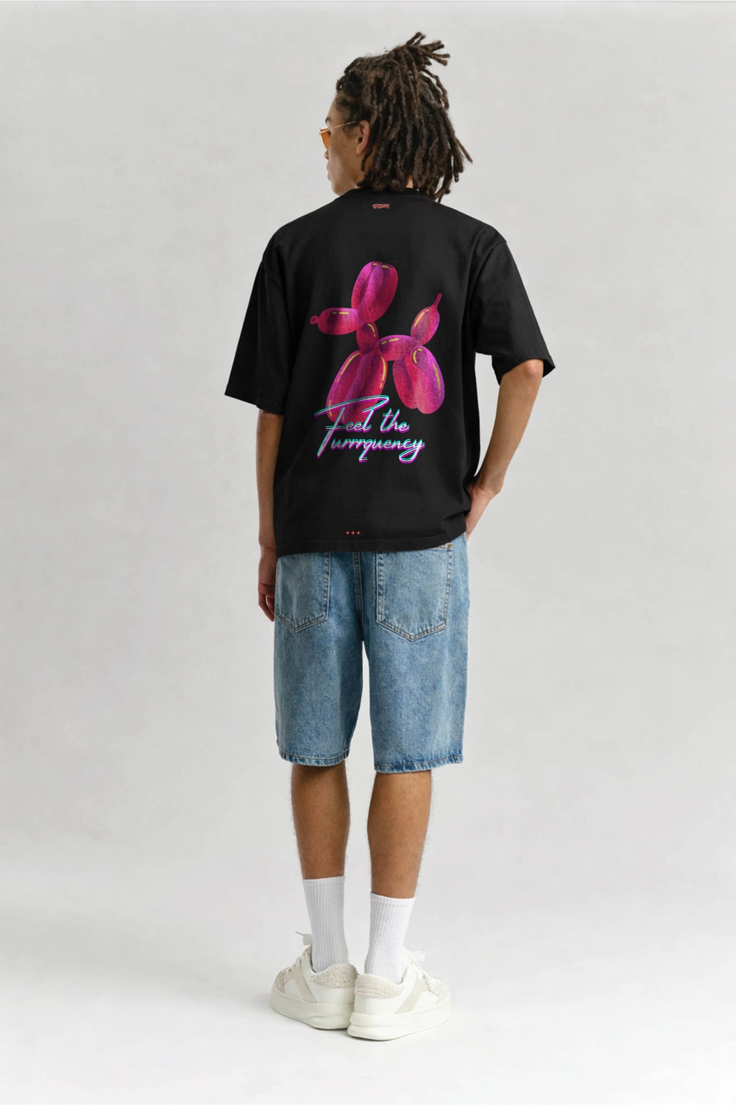 Person wearing a black t-shirt with a pink flower design and text on the back, standing against a plain background.