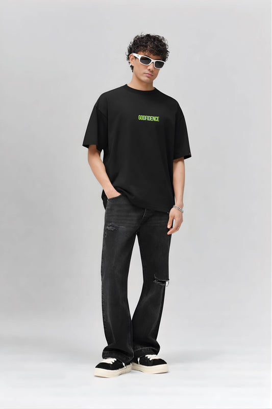 Person wearing a black t-shirt with a brand logo and black jeans on a light gray background