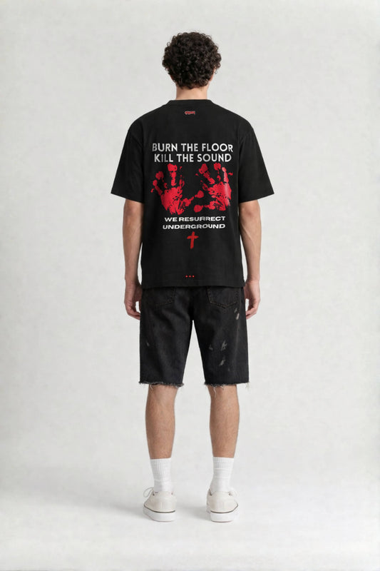 Person wearing a black t-shirt with graphic design and text on the back, standing against a white background.