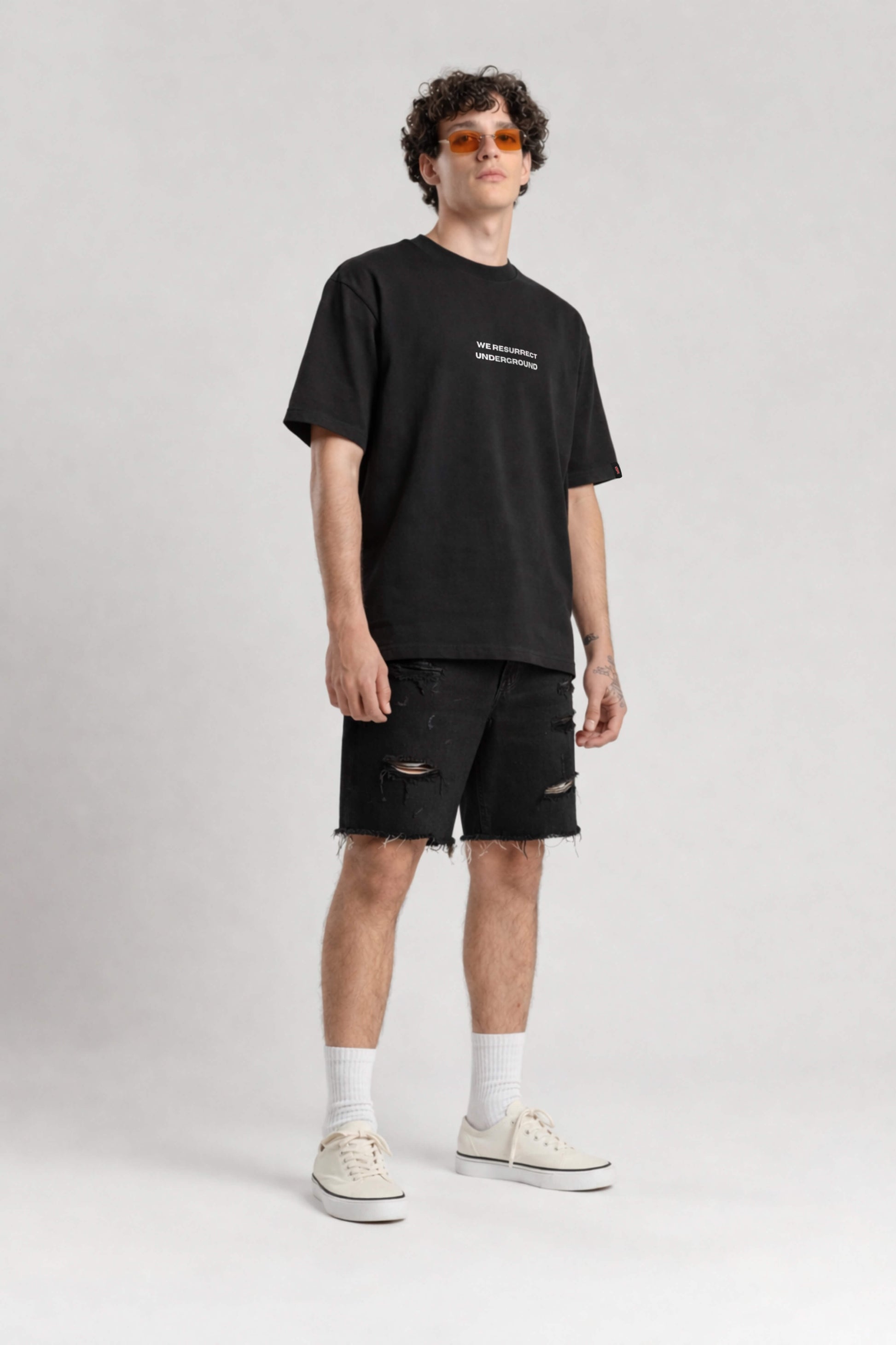 Man wearing a black t-shirt and shorts on a white background