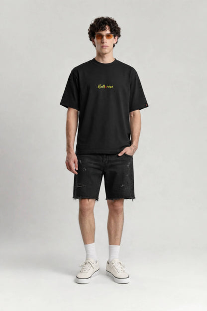 Man wearing a black t-shirt with yellow text and black shorts on a white background