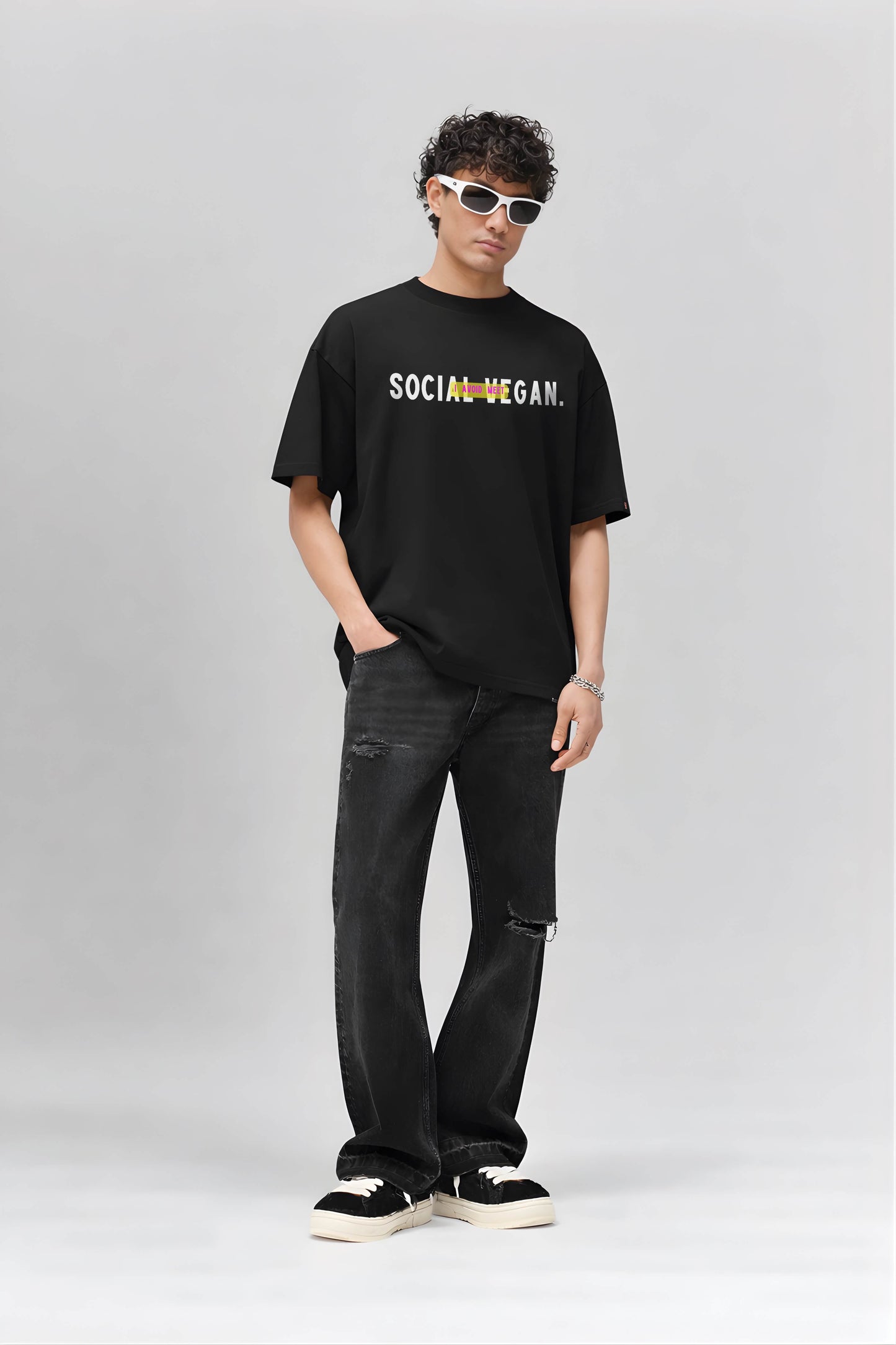 Person wearing a black t-shirt with 'SOCIAL VEGAN' text and black jeans on a light gray background