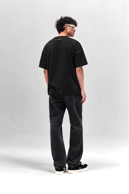 Person wearing a black t-shirt and jeans standing against a white background