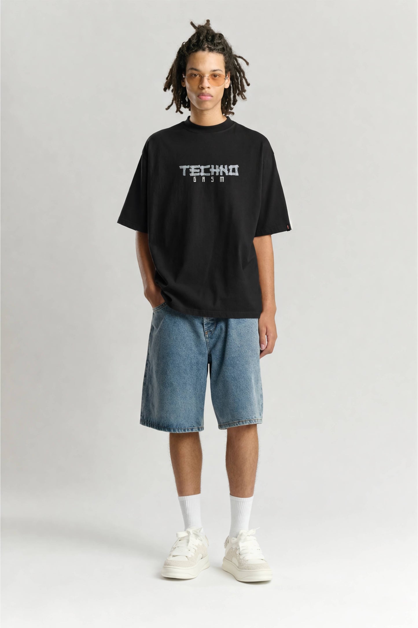 Person wearing a black t-shirt with 'TECHNO' text on a plain background