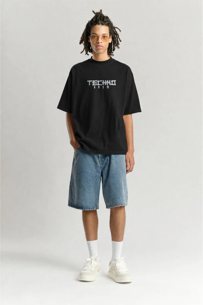 Person wearing a black t-shirt with 'TECHNO' text on a plain background