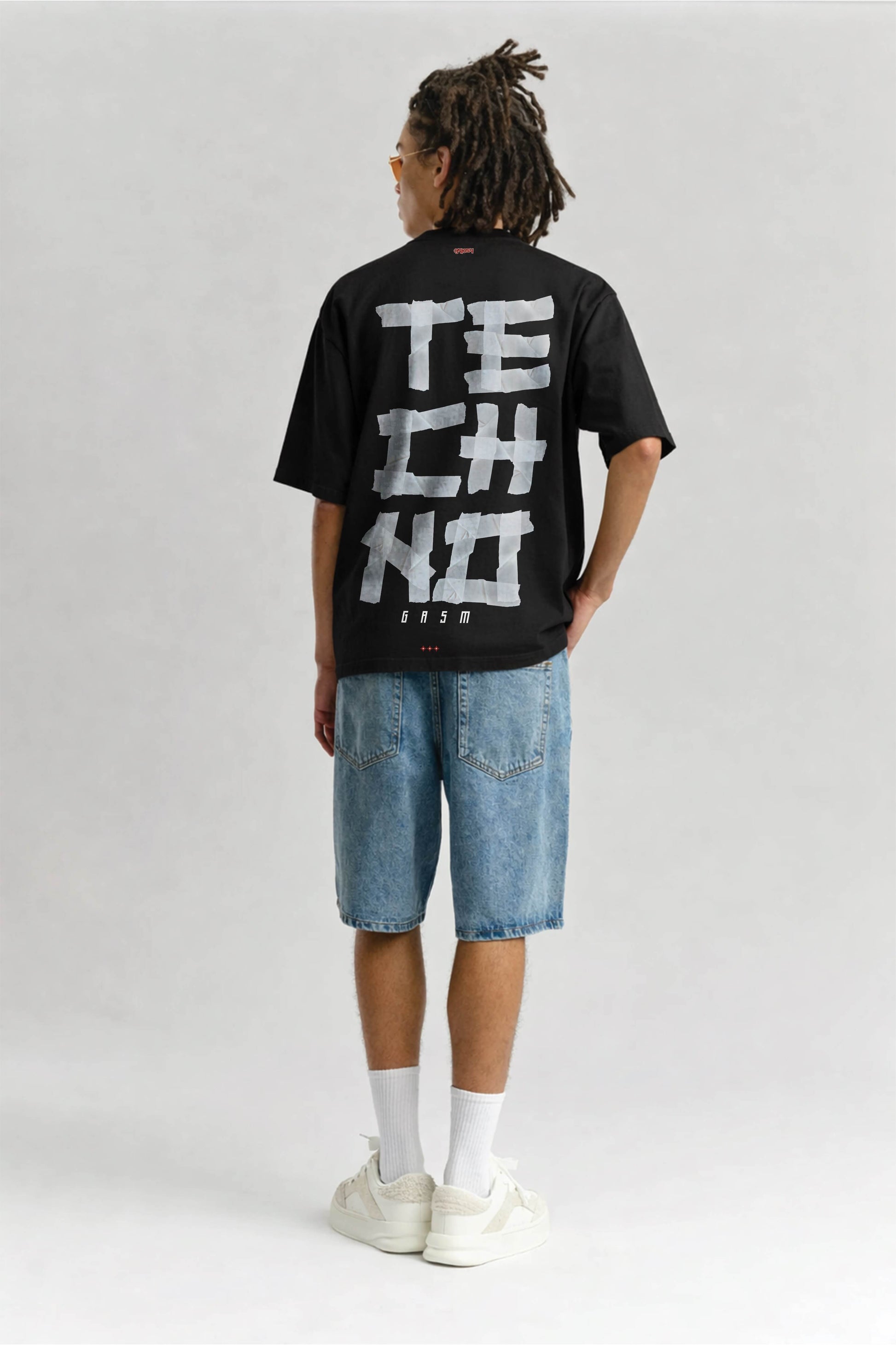 Person wearing a black t-shirt with 'TECHNO' text on the back, standing against a plain background.