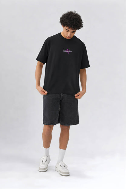 Person wearing a black t-shirt with a logo and dark shorts on a white background