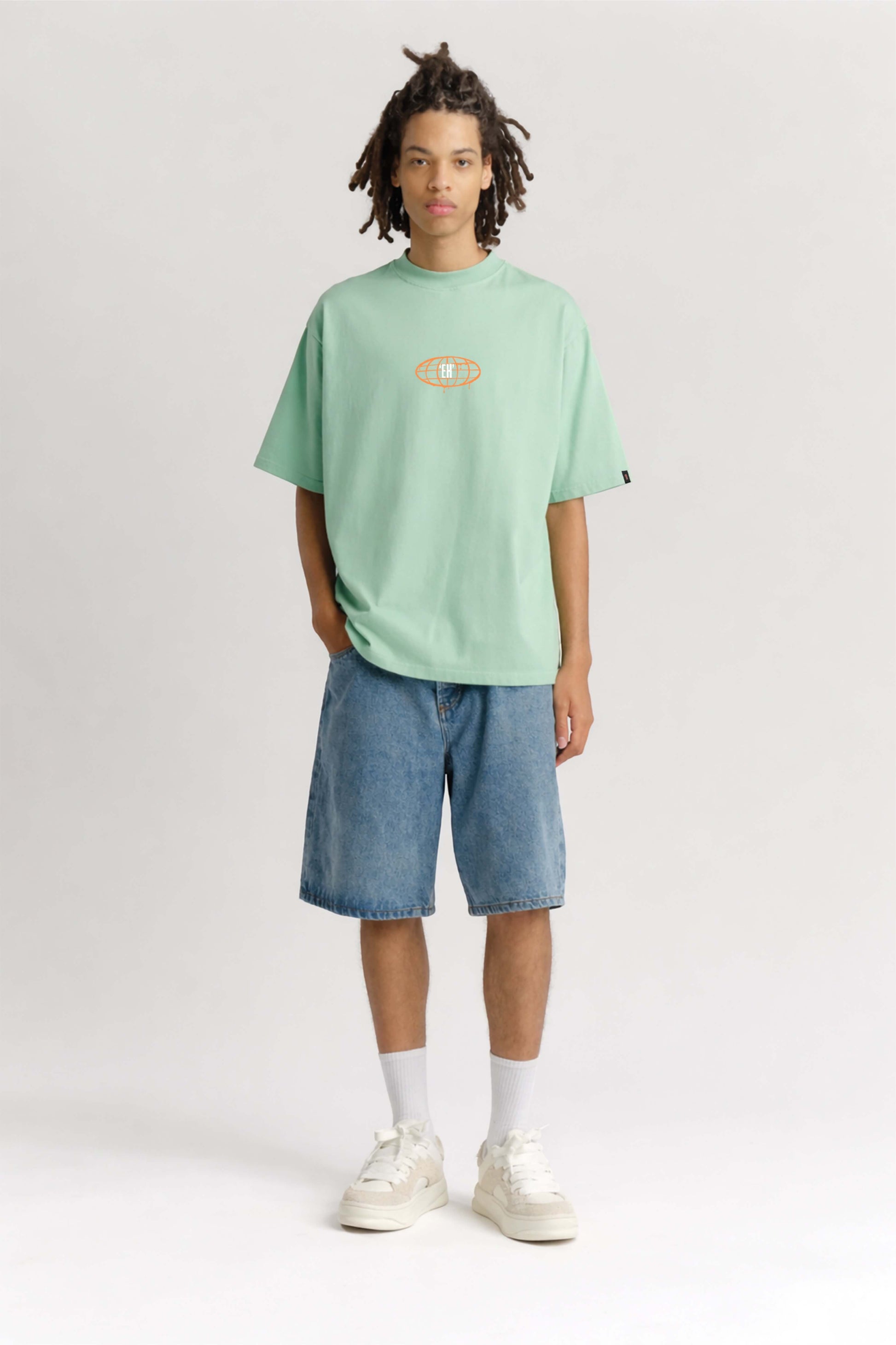 Person wearing a light green t-shirt and blue shorts on a white background