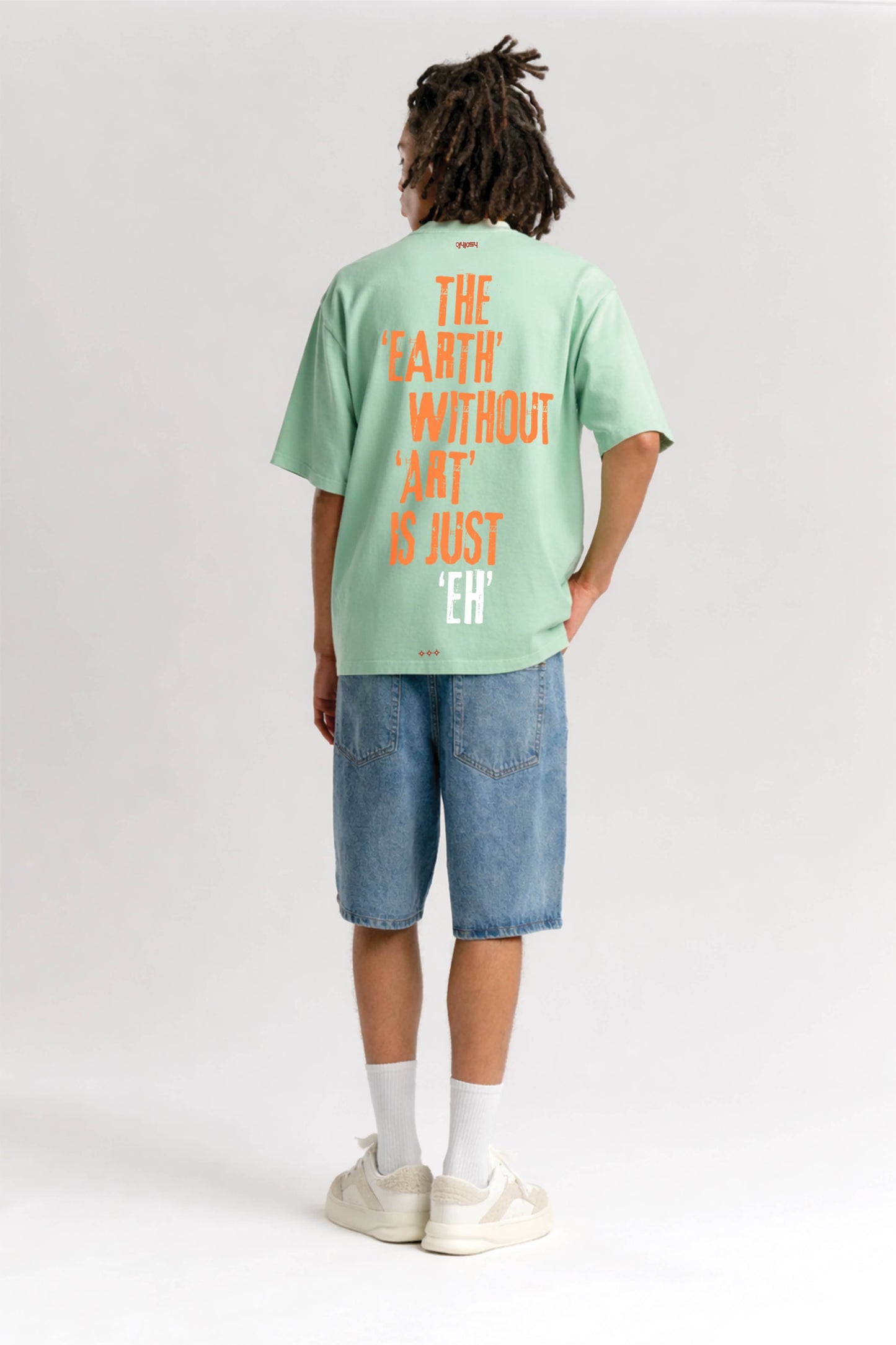 Person wearing a light green t-shirt with text on the back, standing against a white background