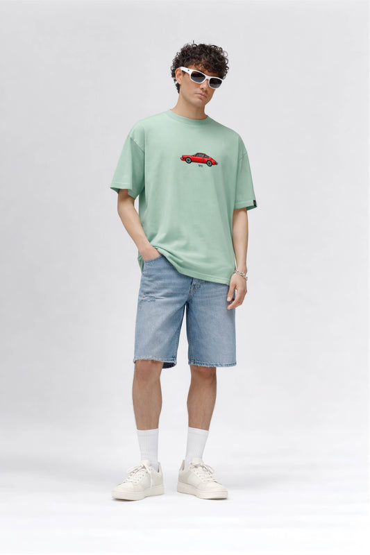 Person wearing a light green t-shirt with a red car graphic and light blue shorts on a white background