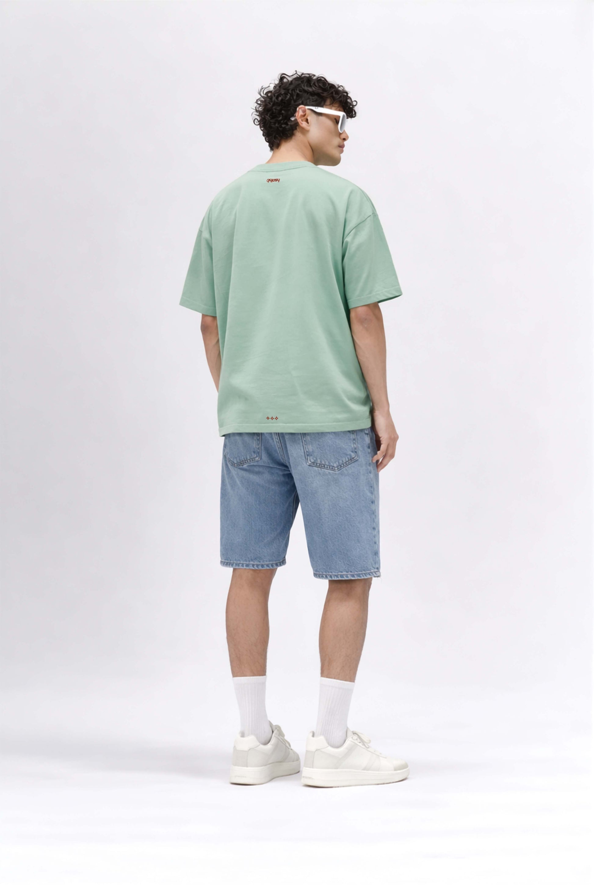 Man wearing a green t-shirt and blue shorts on a white background