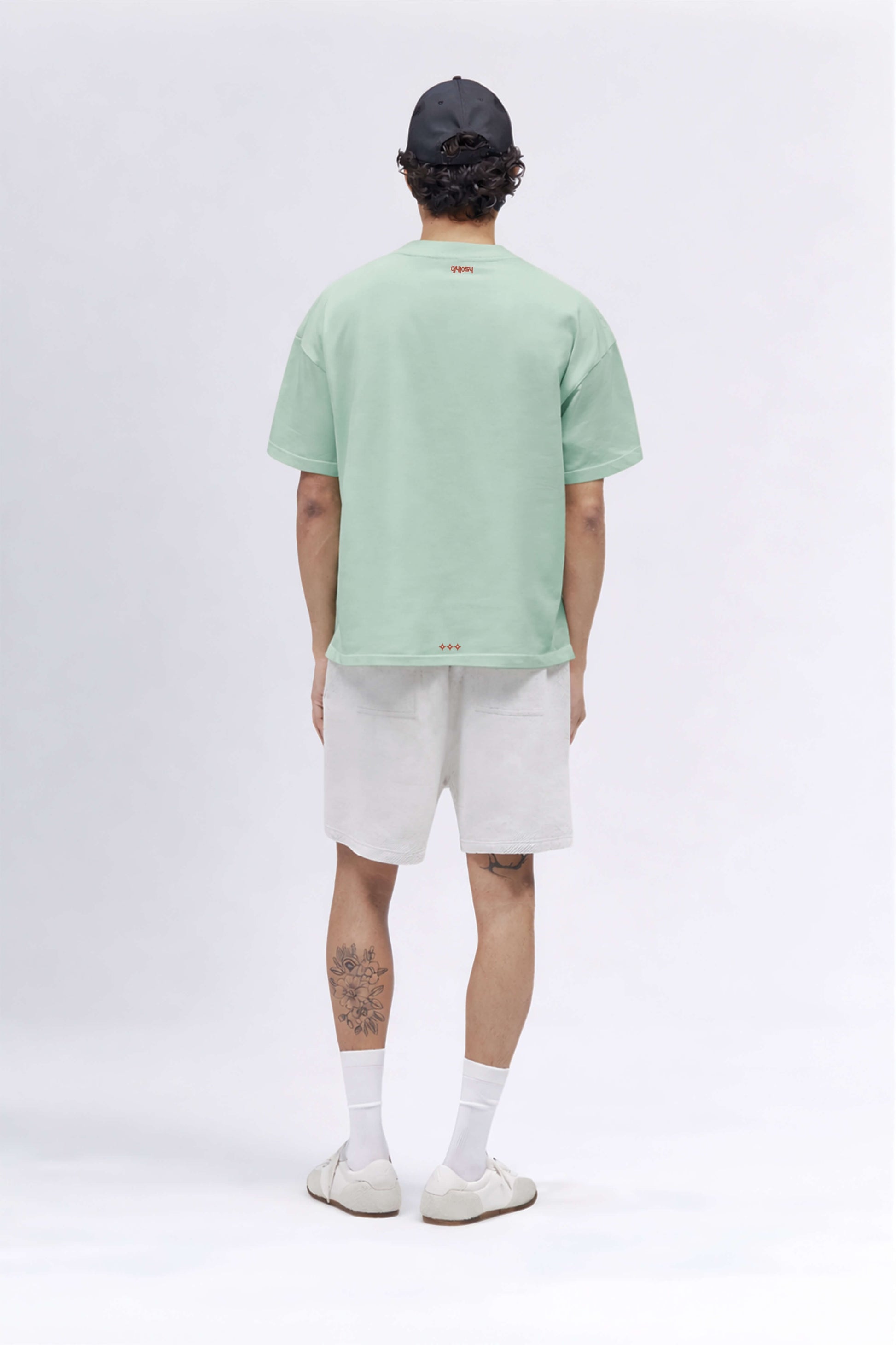 Person wearing a light green t-shirt and white shorts on a plain background