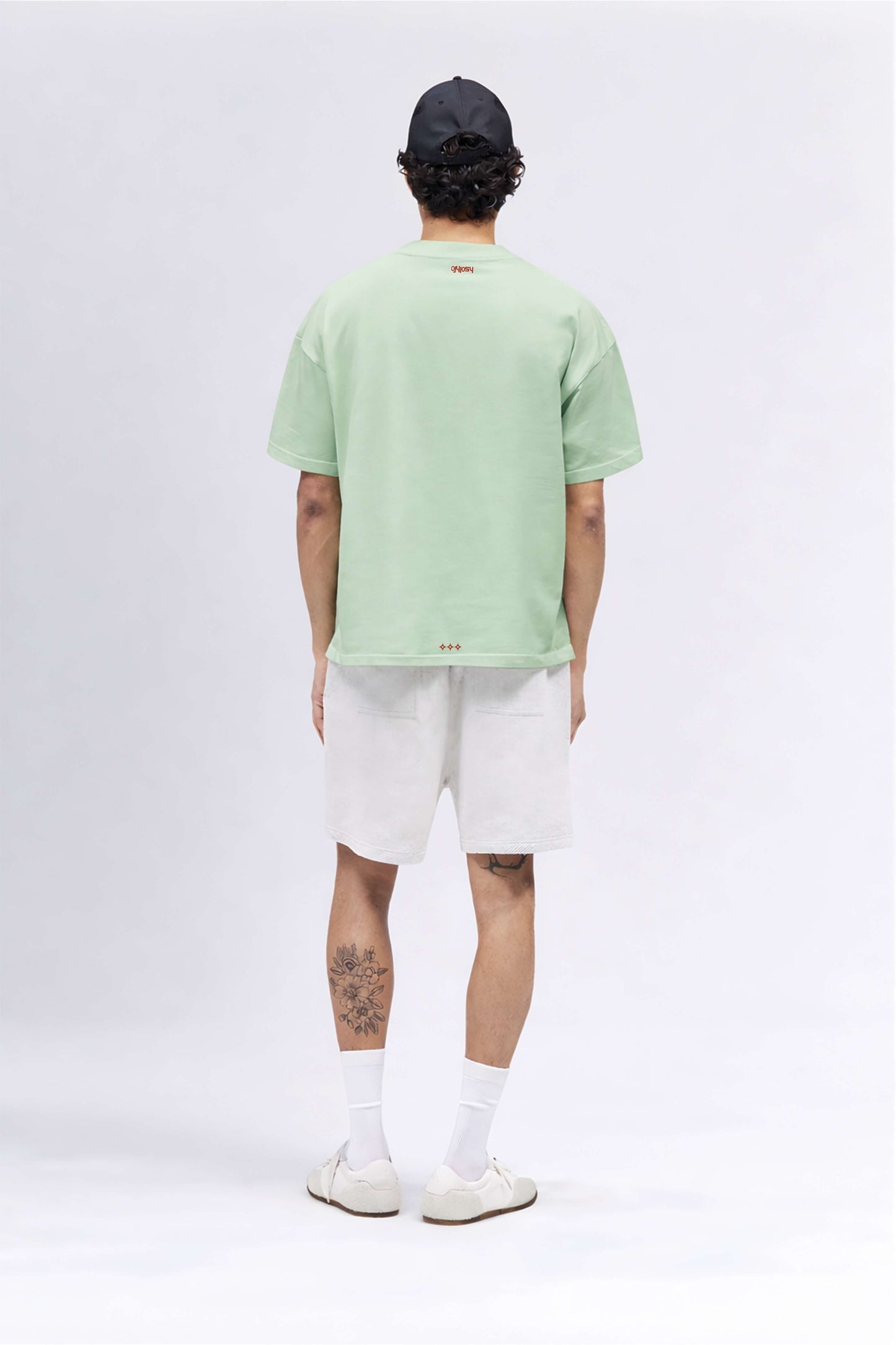 Person wearing a light green t-shirt and white shorts on a white background