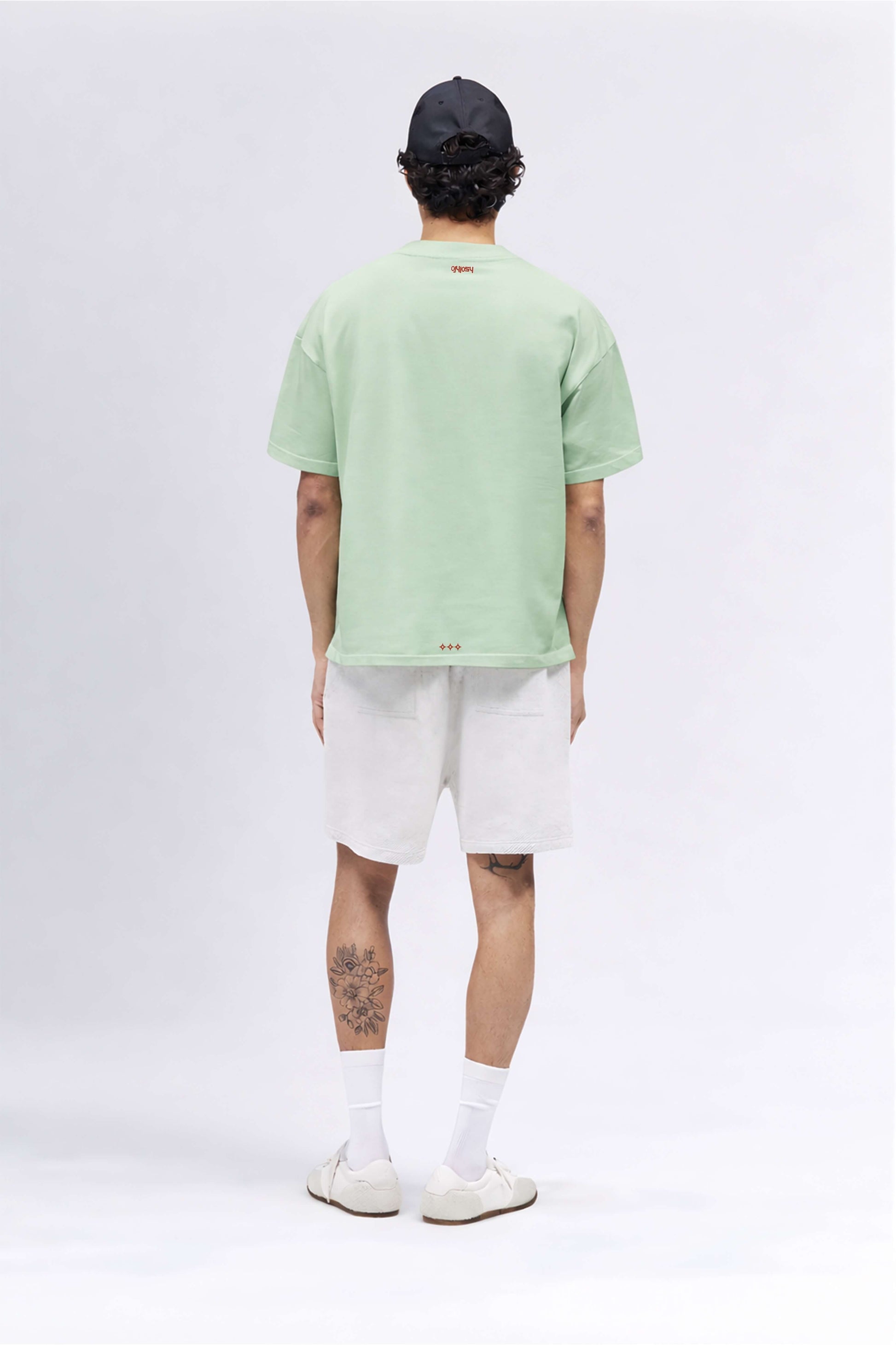 Person wearing a light green t-shirt and white shorts on a white background