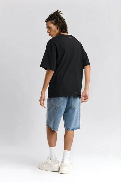 Person wearing a black t-shirt and blue denim shorts on a white background