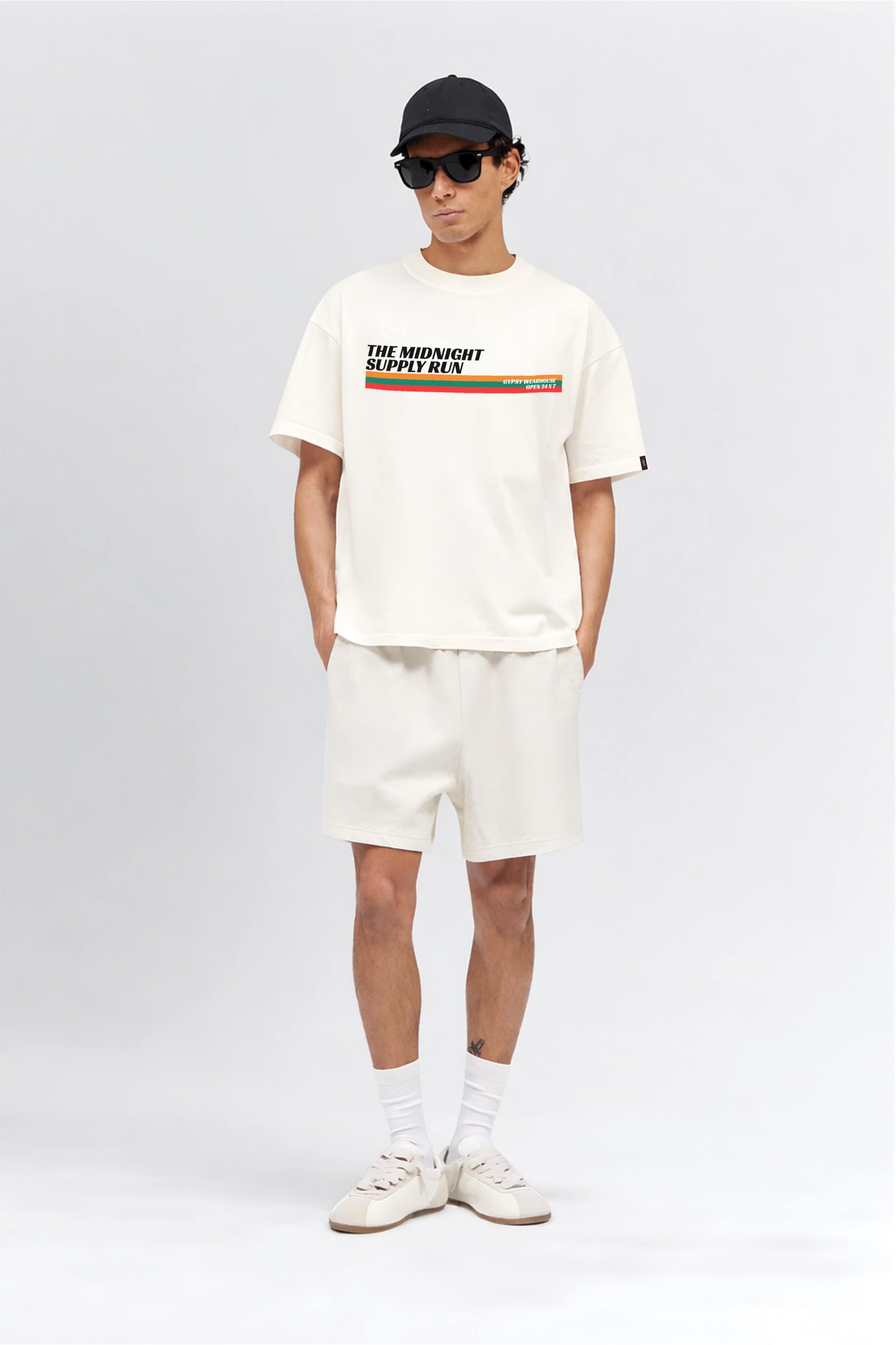 Person wearing a white t-shirt with a graphic design, white shorts, and white sneakers on a white background