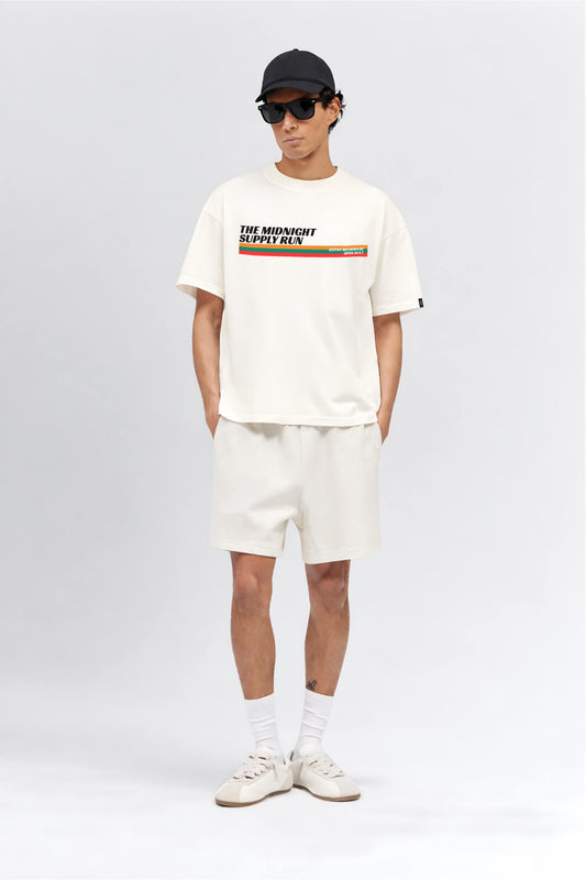Person wearing a white t-shirt with a graphic design, white shorts, and white sneakers on a white background