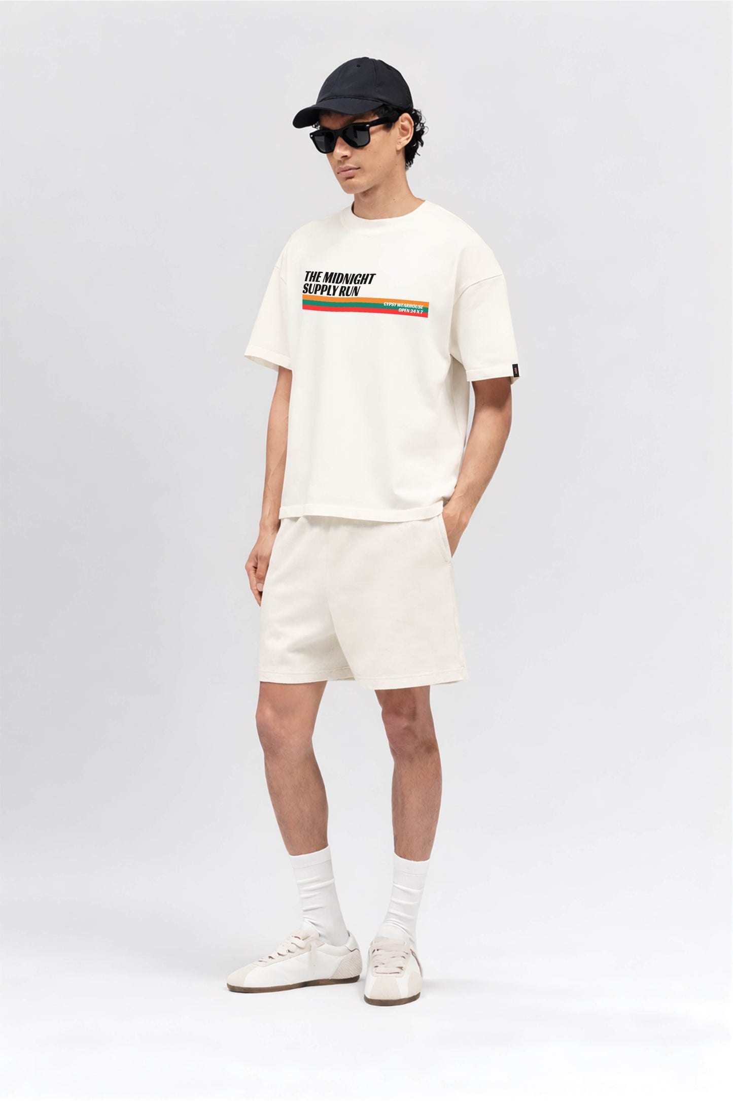 Person wearing a white t-shirt with text and graphics, shorts, and sneakers on a white background