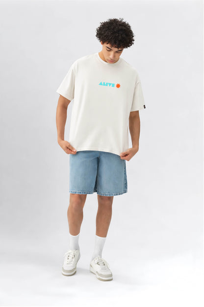 Person wearing an offwhite t-shirt with colorful text and light blue shorts on a white background