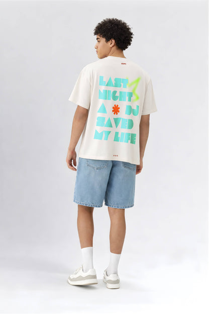 Person wearing an off white t-shirt with colorful text and denim shorts on a white background