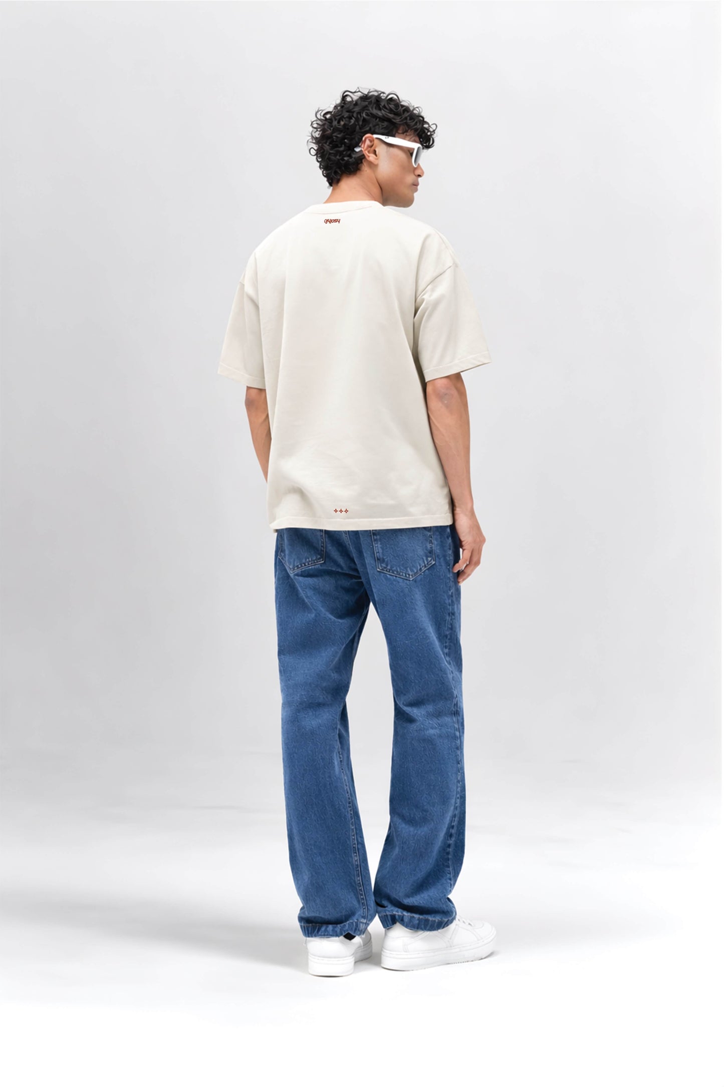 Person wearing an off white t-shirt and blue jeans on a white background