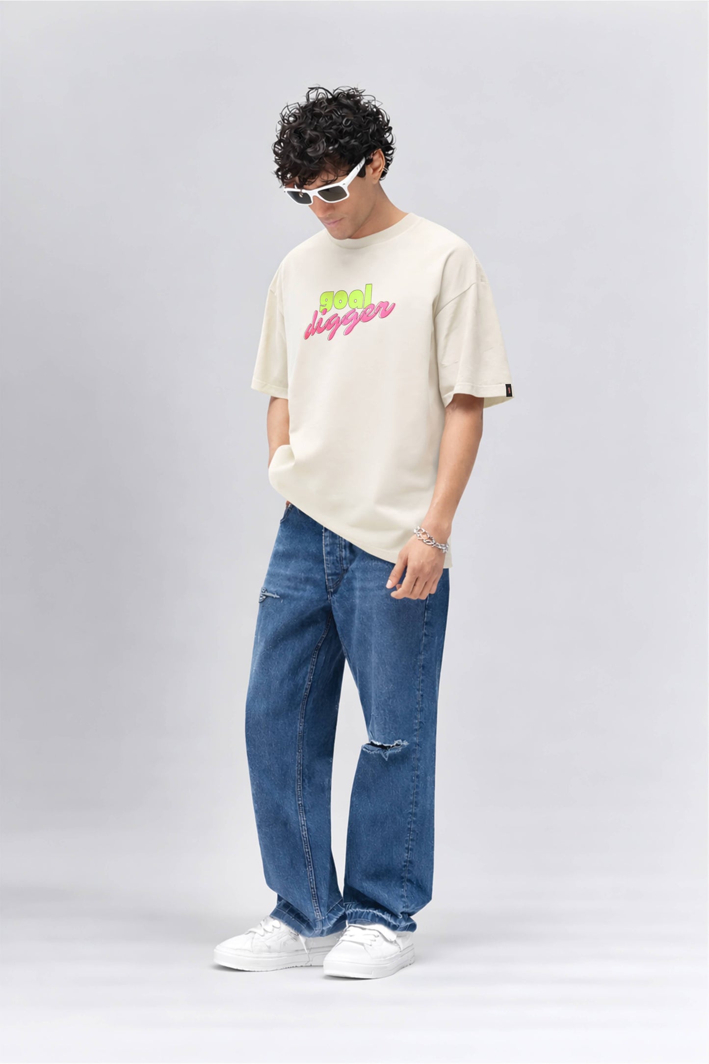 Person wearing a off white t-shirt with text and blue jeans on a white background