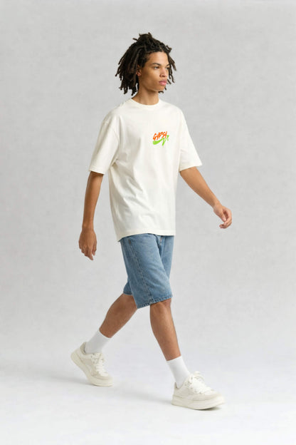 Person wearing an offwhite t-shirt with a colorful design and blue shorts on a light gray background