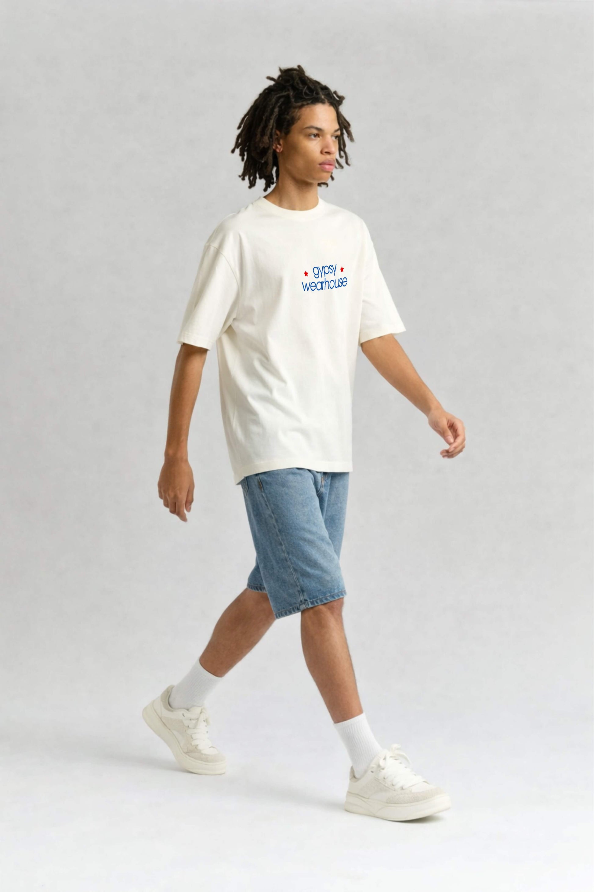 Person wearing a white t-shirt with text and blue shorts on a light gray background