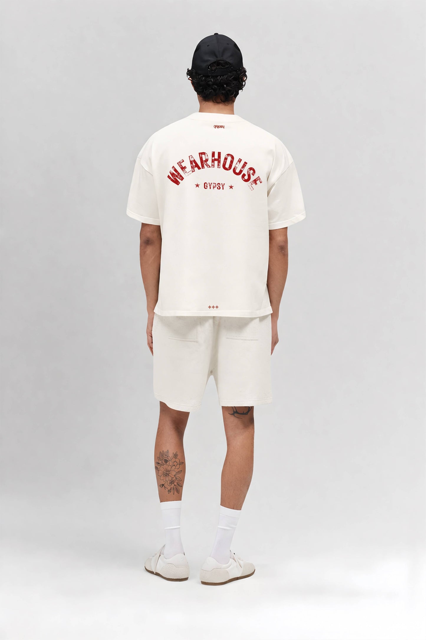 Person wearing an off white t-shirt with text and shorts on a gray background