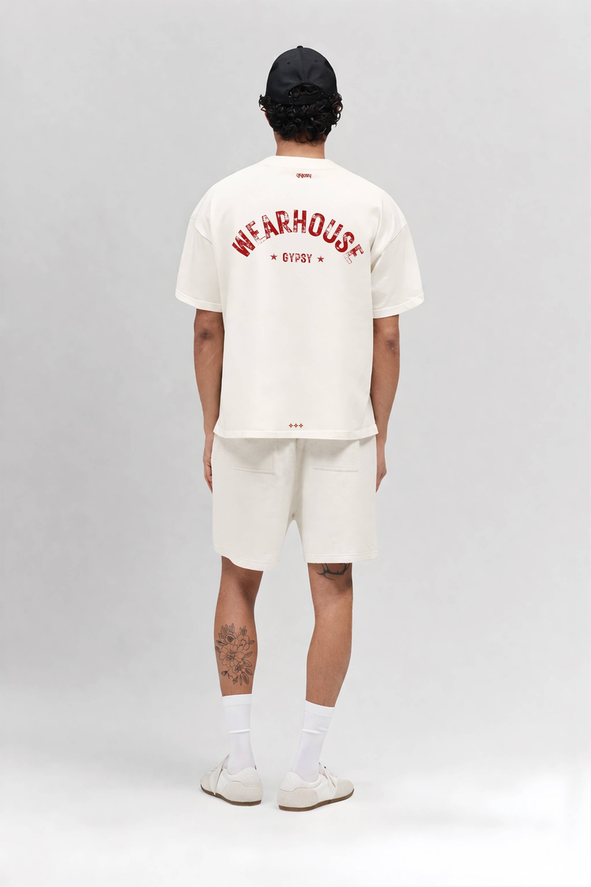 Person wearing an off white t-shirt with text and shorts on a gray background