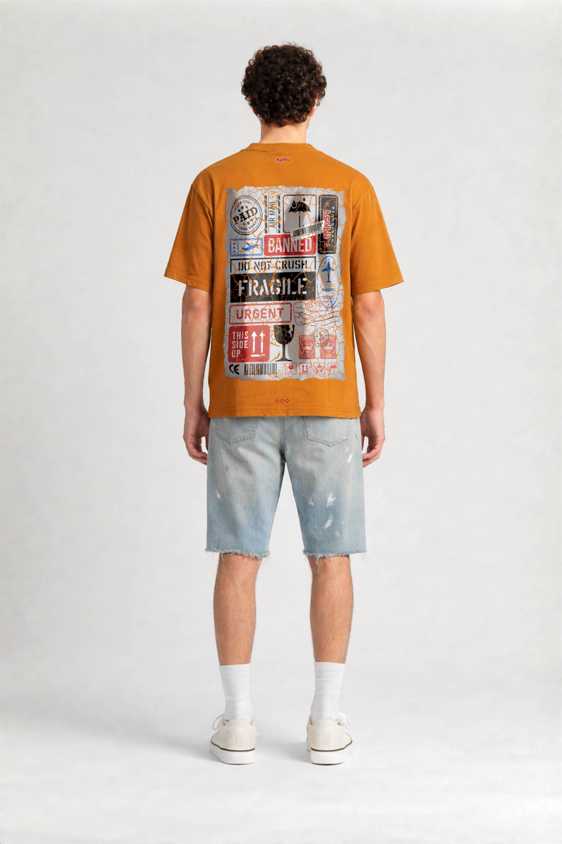 Person wearing an orange t-shirt with a graphic design on the back, standing against a white background