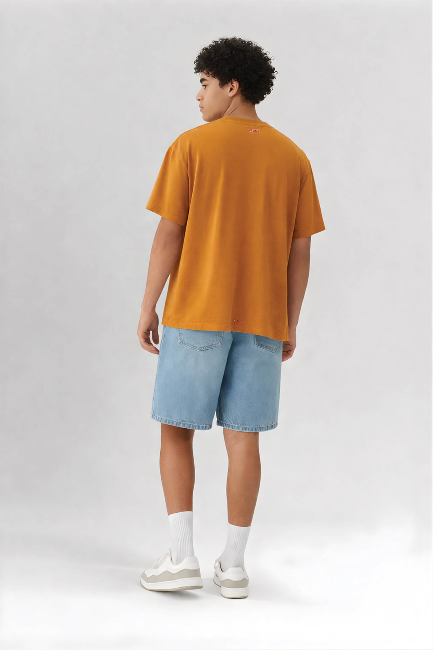 Person wearing a orange t-shirt and light blue shorts on a white background